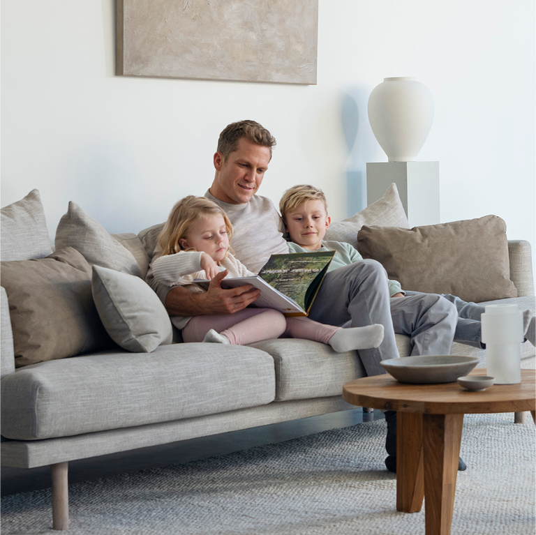 Blueair A father reading to a children sitting on a couch